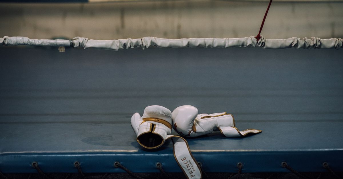 White boxing gloves resting inside an empty boxing ring, symbolizing sports intensity.